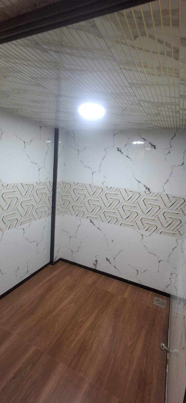 Marble-clad steam room with wood-finish flooring